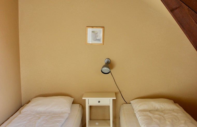 Sfeervolle slaapkamer in Vakantiehuisje in Gulpen, Zuid Limburg, met comfortabele bedden en rustgevende ambiance.