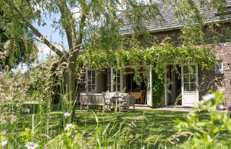Zonnig terras met houten tafel bij Huisje in Slenaken vakantiehuis in Limburg.