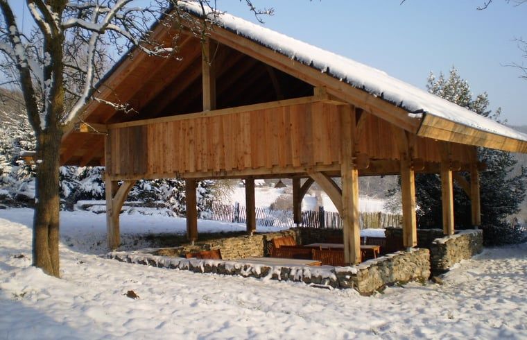 Vacation home in Vijlen, South Limburg, with an attractive wooden veranda in a snowy setting for a cozy winter experience.