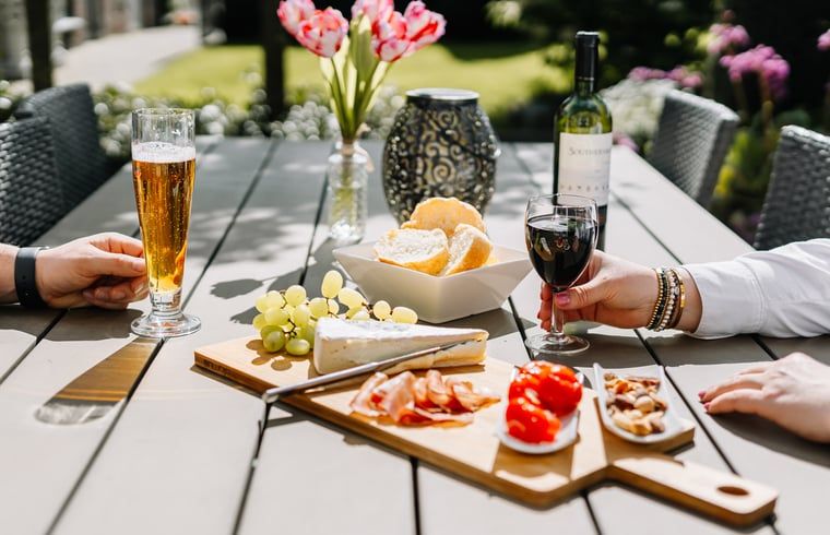 Geniessen Sie einen entspannten Nachmittag auf der Terrasse des Ferienhauses in Gulpen - Wittem, Suedlimburg, mit Wein und Snacks in der Sonne.