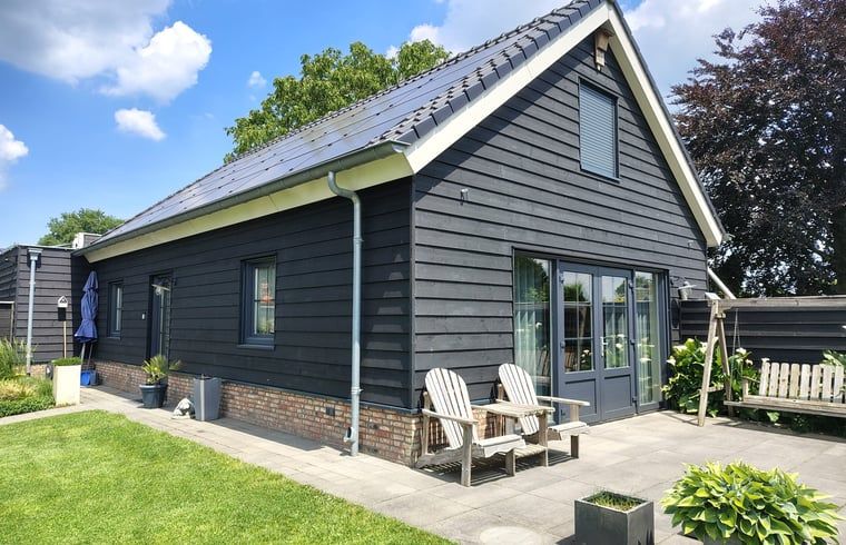 Green garden with flowers and trees at Huisje in Zeeland, a serene vacation home in De Peel, North Brabant.