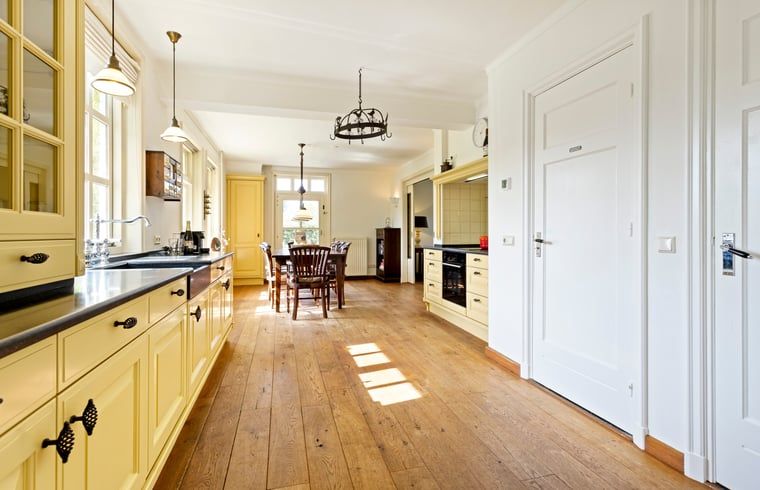 Ruime keuken in Vakantiehuisje in Deurne, Noord Brabant, met houten vloeren en veel lichtinval, ideaal voor een ontspannen verblijf.