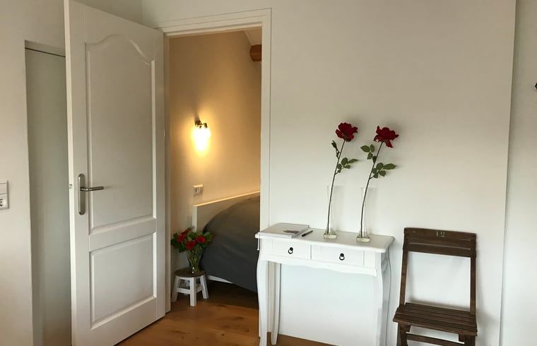 Sfeervolle slaapkamer in Huisje in Baarle-Nassau, vakantiehuis in Noord Brabant, met houten details.