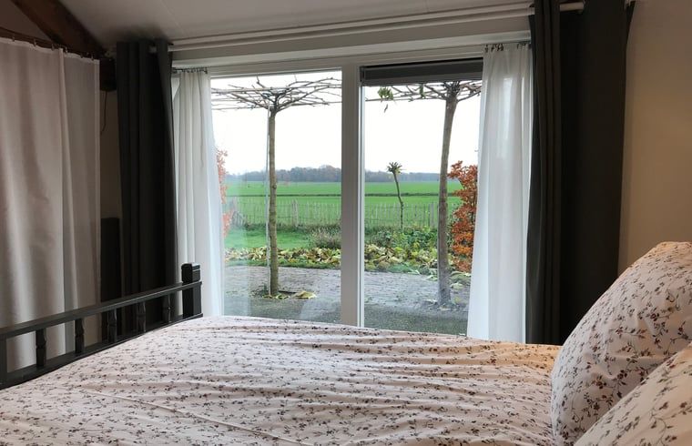 Slaapkamer met uitzicht op de tuin bij Huisje in Baarle-Nassau, vakantiehuis in Noord Brabant.