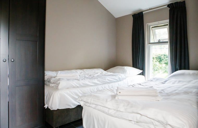 Komfortables Schlafzimmer im Ferienhaus in Oirschot, gelegen in der laendlichen Region Kempen in Nordbrabant, mit Blick auf die gruene Natur.