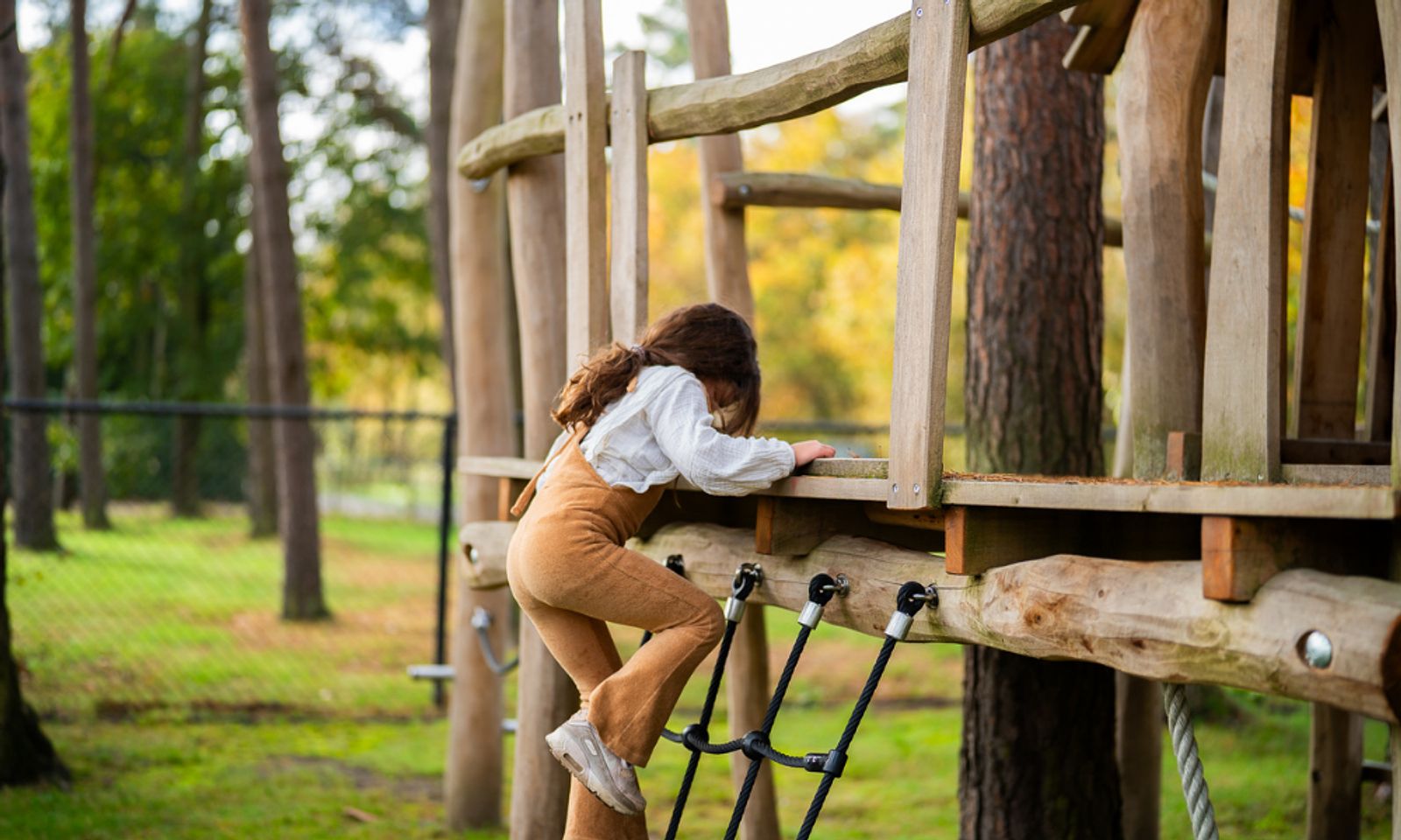 Kind klimt op de speeltuin bij White Lodge vakantiehuis, Veldhoven, Kempen, Noord Brabant.