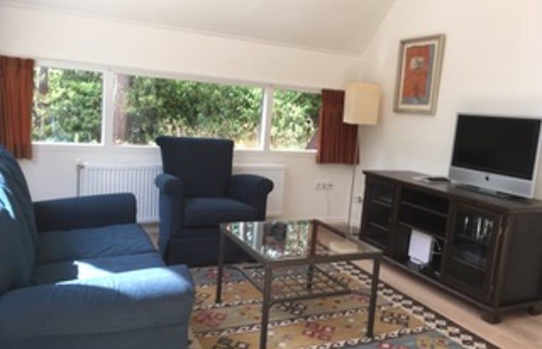 Cozy living room of cottage in Eersel, North Brabant, with comfortable seating and views of the green nature of the Kempen.