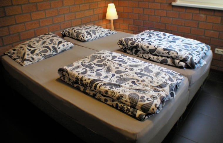 Slaapzaal in Vakantiehuisje in Luyksgestel met meerdere bedden, ideaal voor groepen of families.