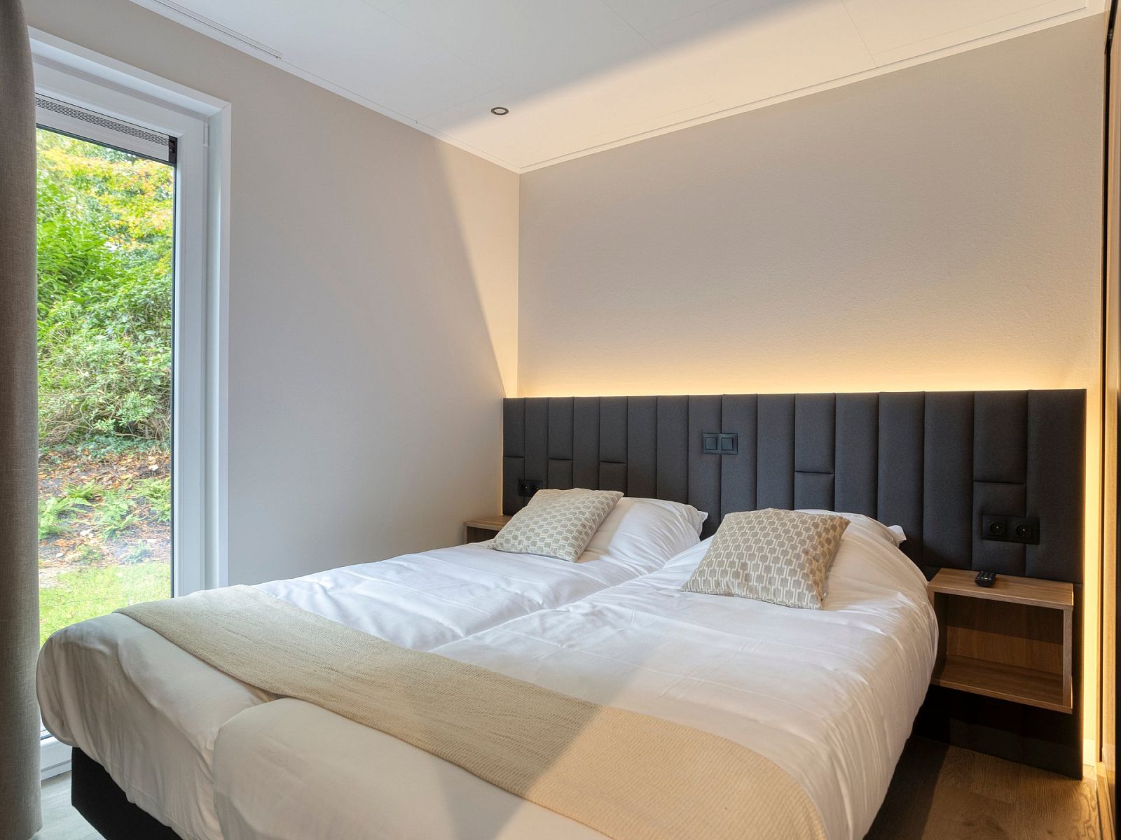 Sfeervolle slaapkamer in vakantiehuis Bosven, Oisterwijk, Hart van Brabant, met uitzicht op de groene natuur van Noord Brabant.