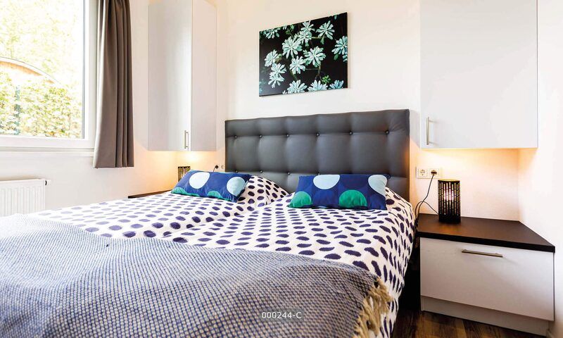 Gezellige slaapkamer in Z Module 6 personen Wellness, Cromvoirt, met kunst aan de muur en veel natuurlijk licht.