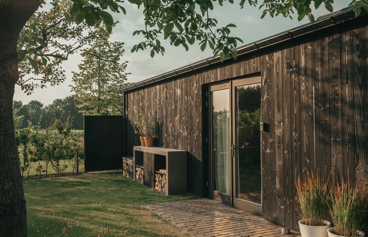 Sunny garden of Holiday Home in Chaam, North Brabant with modern wooden finishes and natural surroundings.