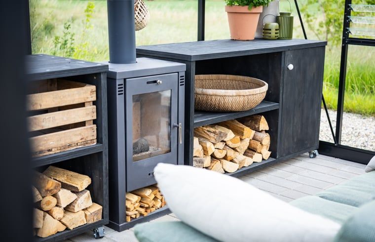 Wood-burning stove in glass room of Holiday Home in Chaam, North Brabant, for cozy evenings.