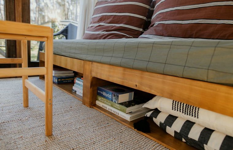 Opbergruimte onder de bank in Vakantiehuis in Diessen, Noord Brabant, met boeken en kussens.