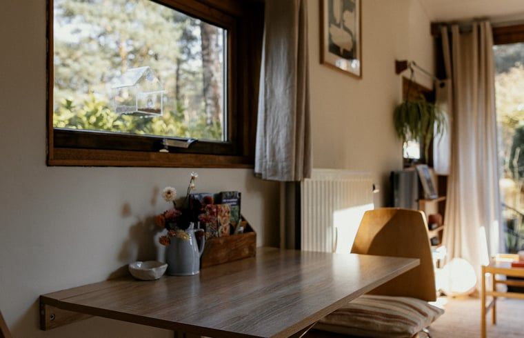 Eettafel bij het raam in Vakantiehuis in Diessen, Noord Brabant, met uitzicht op de tuin.