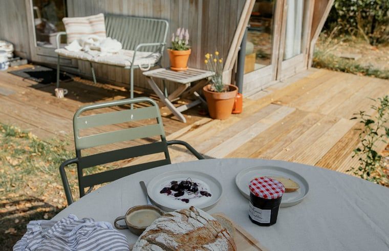 Buitenterras van Vakantiehuis in Diessen, Noord Brabant, met ontbijtset en bloemen.