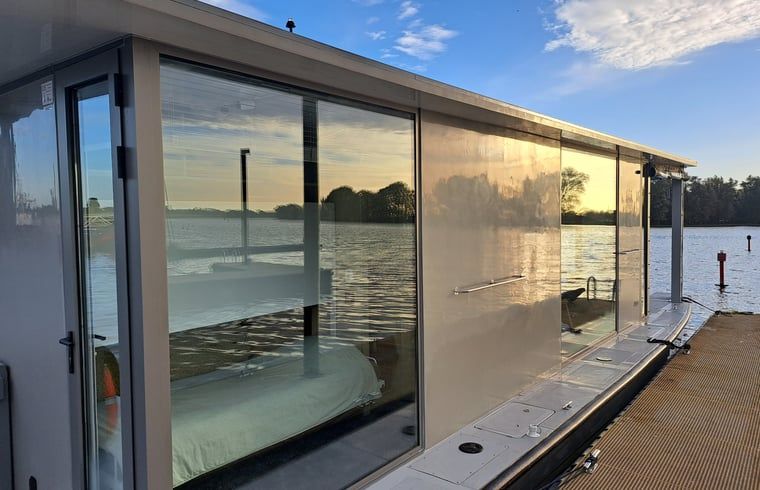 In der Glasfassade des Ferienhauses in Woudrichem spiegelt sich der Sonnenuntergang, Nordbrabant.
