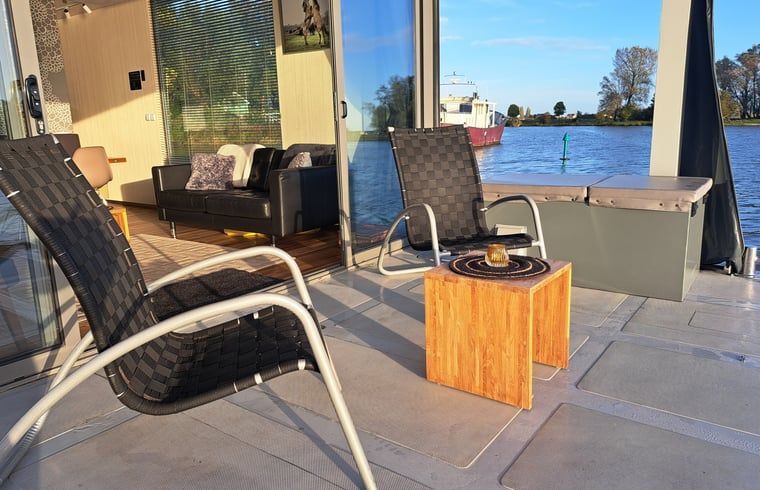 Terrasse mit Liegestuehlen im Ferienhaus in Woudrichem, Hart van Brabant, Nordbrabant.