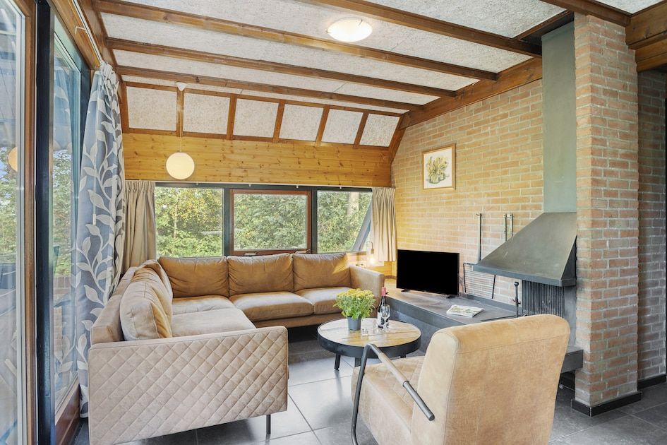 Cozy living room of Bosrand B 6 bungalow in Herpen, Northeast Brabant, with comfortable seating area and views of green nature.