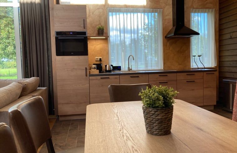 Moderne keuken en eetruimte in Vakantiehuis in Schaijk, Noord Brabant met uitzicht op de tuin.