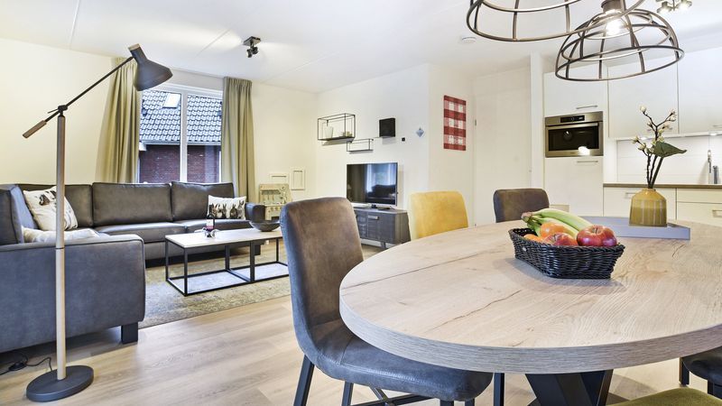 Moderne woonkamer in De Vers 6-persoons kinderbungalow Overloon met eetgedeelte en open keuken.