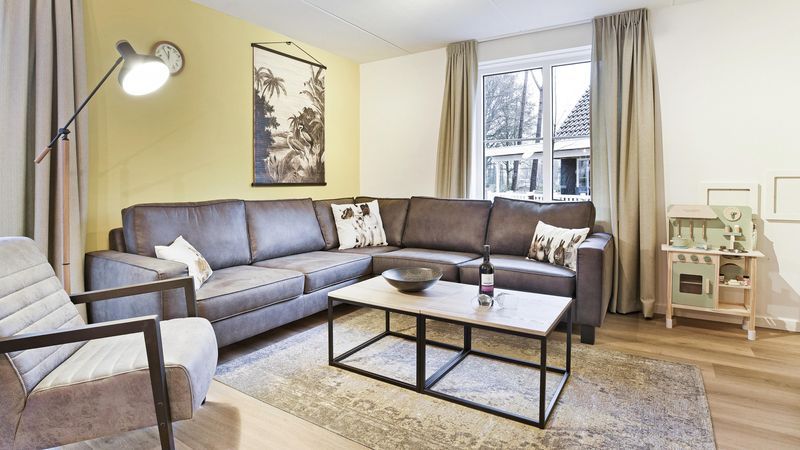 Gezellige zithoek in De Vers kinderbungalow Overloon, Noordoost Brabant, met comfortabele bank.