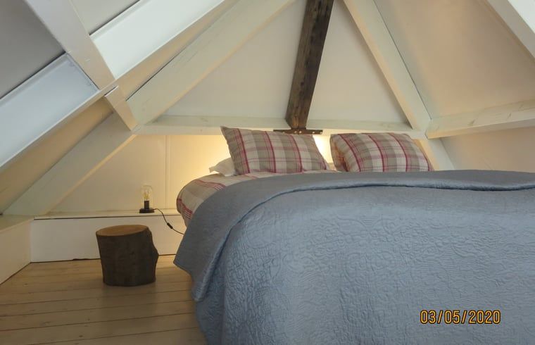 Sfeervolle slaapkamer met houten balken in Vakantiehuis in Oeffelt, Noord Brabant.