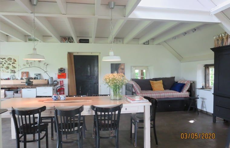 Ruime woonkamer met bloemen in Vakantiehuis in Oeffelt, Noordoost Brabant.