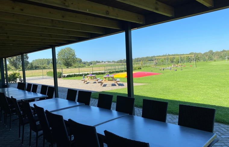 Geniet van het uitzicht op het groene landschap vanaf de veranda van Huisje in Nistelrode, een gezellig vakantiehuis in Noordoost Brabant.