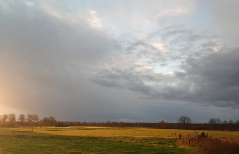 Weids uitzicht op velden bij Vakantiehuis in Erp, Noord Brabant, met wolkenlucht.