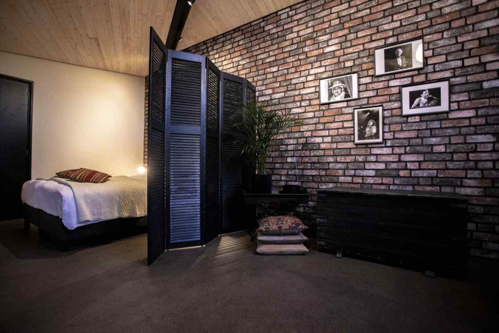 Attractive bedroom in BRA045 vacation home Geffen with brick wall and artwork.