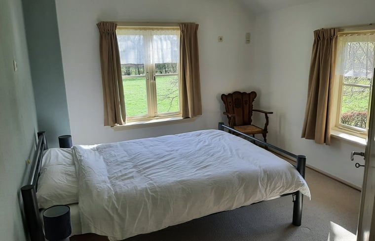 Sfeervolle slaapkamer in Vakantiehuisje in Keent, Noordoost Brabant, met uitzicht op groene velden en rustieke inrichting.