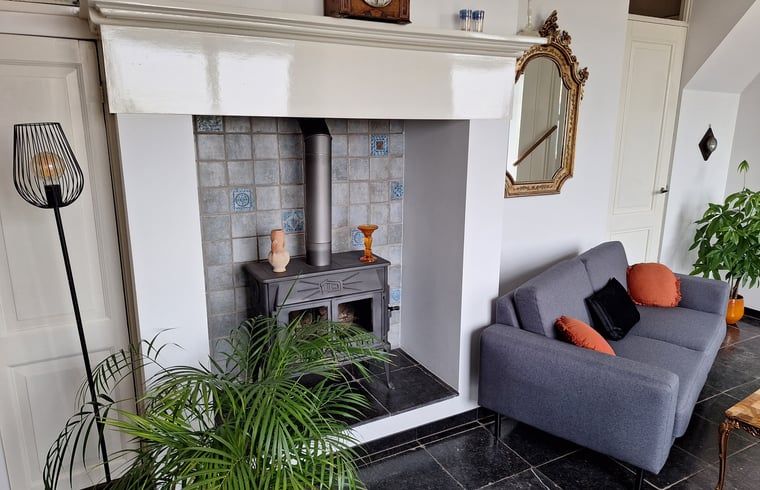 Sfeervolle woonkamer met houtkachel in Vakantiehuisje in Ossendrecht.