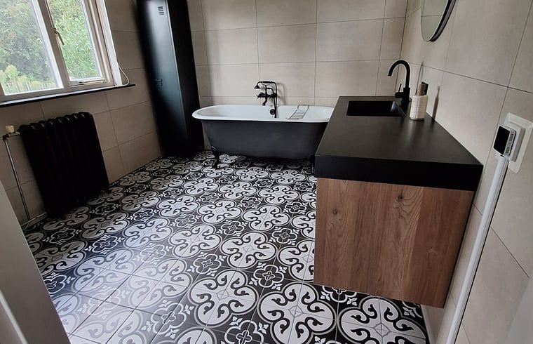 Stijlvolle badkamer met vrijstaand bad in Vakantiehuisje in Ossendrecht.