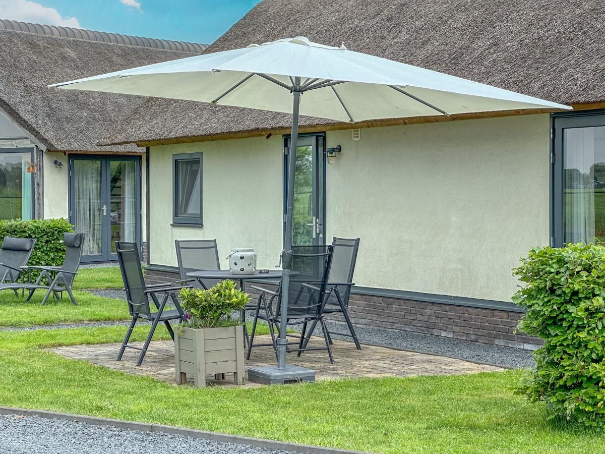 Sunny terrace with parasol at Villa Bianco vacation home, Alphen, North Brabant.