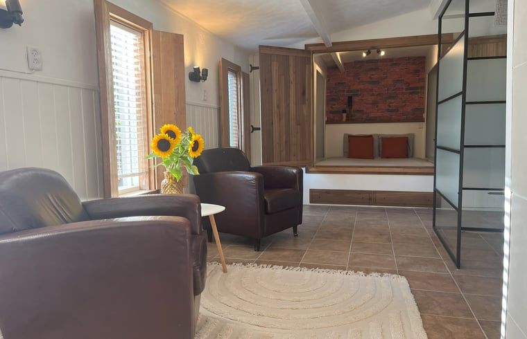 Geraeumige Sitzecke im Cottage in Hoogerheide, Ferienhaus in Hoogerheide, mit Ledersesseln und einem Fernseher.