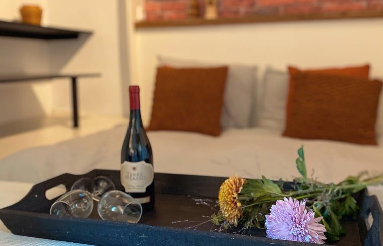 Romantisches Schlafzimmer in Cottage in Hoogerheide, Ferienhaus in Hoogerheide, mit Wein und Blumen auf einem Tablett.