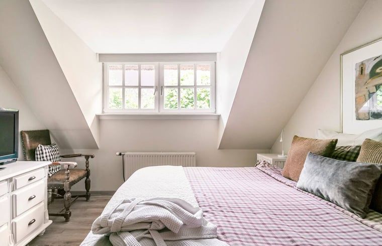 Lichte slaapkamer met houten kast in vakantiehuis in Roosendaal, Noord Brabant.