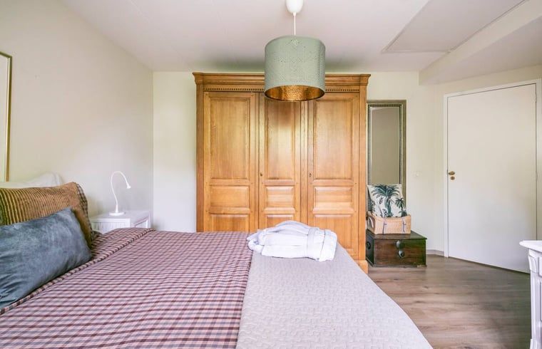 Gezellige slaapkamer met oranje accenten in vakantiehuis in Roosendaal, Noord Brabant.