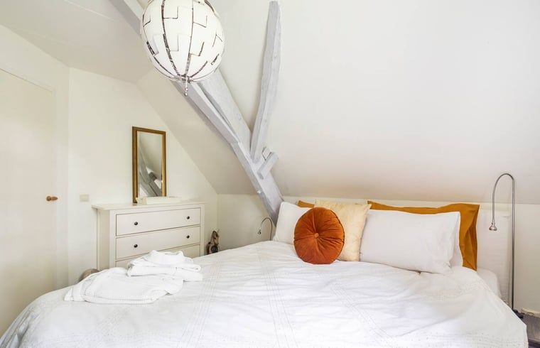 Lichte slaapkamer met kunstwerk in vakantiehuis in Roosendaal, West Brabant.