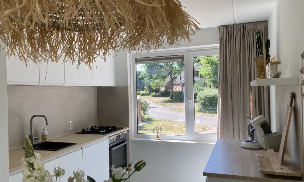 Moderne keuken in Villa Wellness Retreat, een vakantiehuis in Halderberge, West Brabant, met uitzicht op groene omgeving.