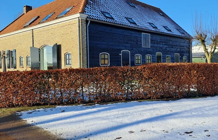 Winterfassade des Hauses in Drimmelen, Ferienhaus in Nordbrabant mit schneebedeckter Hecke.