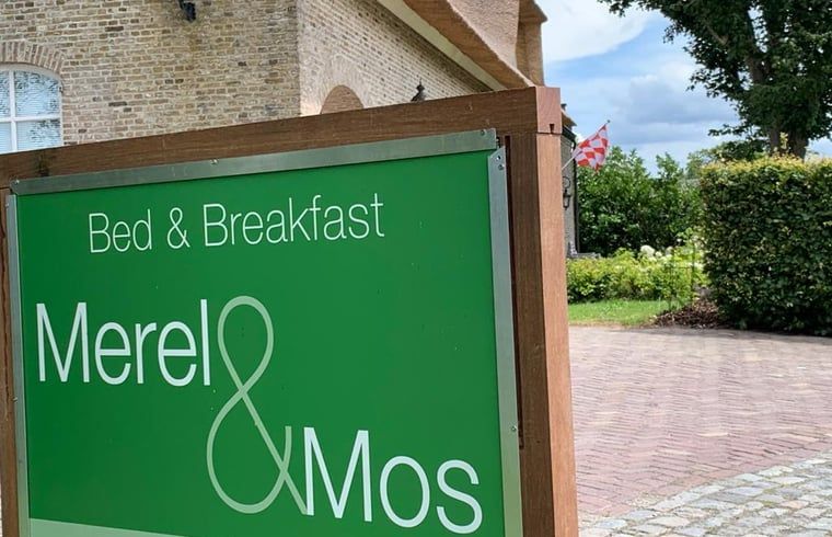 Ontdek de charmante Bed & Breakfast Merel & Mos in Moerstraten, West Brabant, met een uitnodigend bord en groene omgeving.