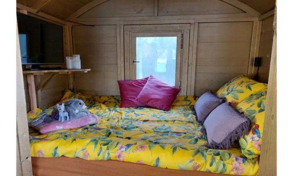 Comfortabele slaapkamer in Wagen Cosy, Spaarndam, met kleurrijk beddengoed en knusse sfeer, ideaal voor een bijzondere overnachting in Noord-Holland.