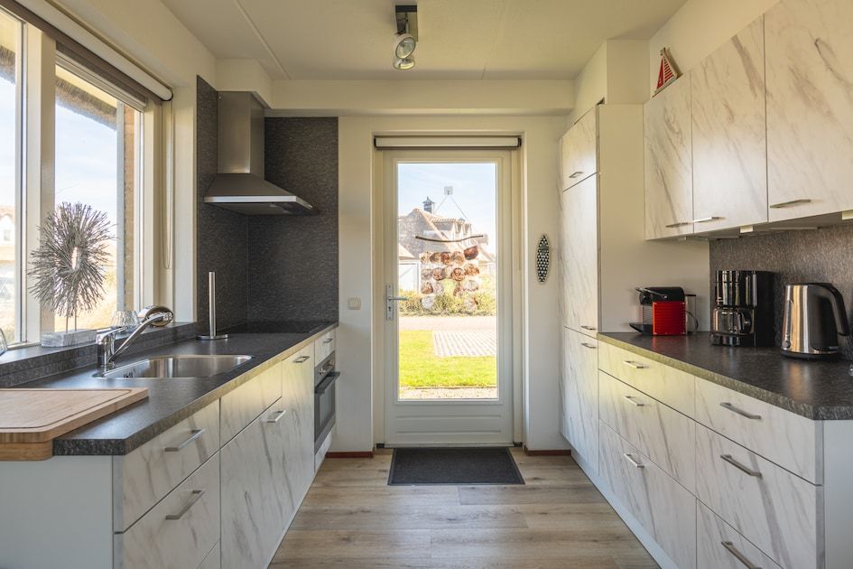Moderne keuken in Villa Luxe 6, vakantiehuis aan de Noordzeekust in Julianadorp, Noord-Holland, met uitzicht op de tuin.