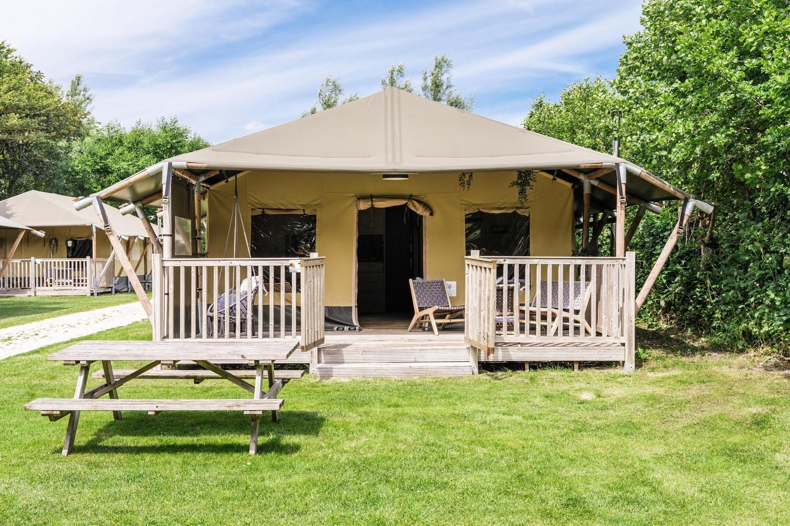 Strandtent 8 personen in Julianadorp, Noord-Holland, biedt een glamping ervaring met een ruime veranda en uitzicht op de groene omgeving.