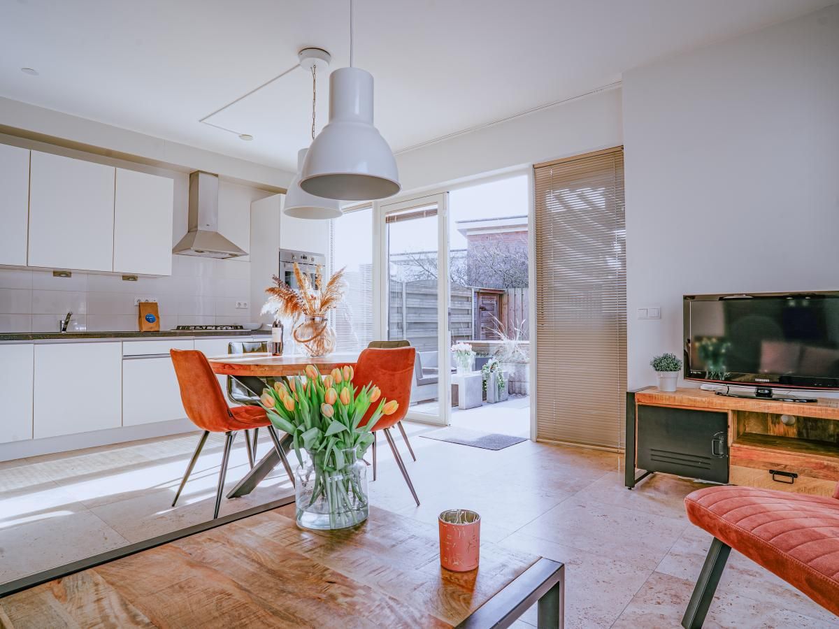 Modernes Wohnzimmer des Ferienhauses Zeebaars in Egmond aan Zee mit offener Kueche und Gartenblick, Nordseekueste, Nordholland.