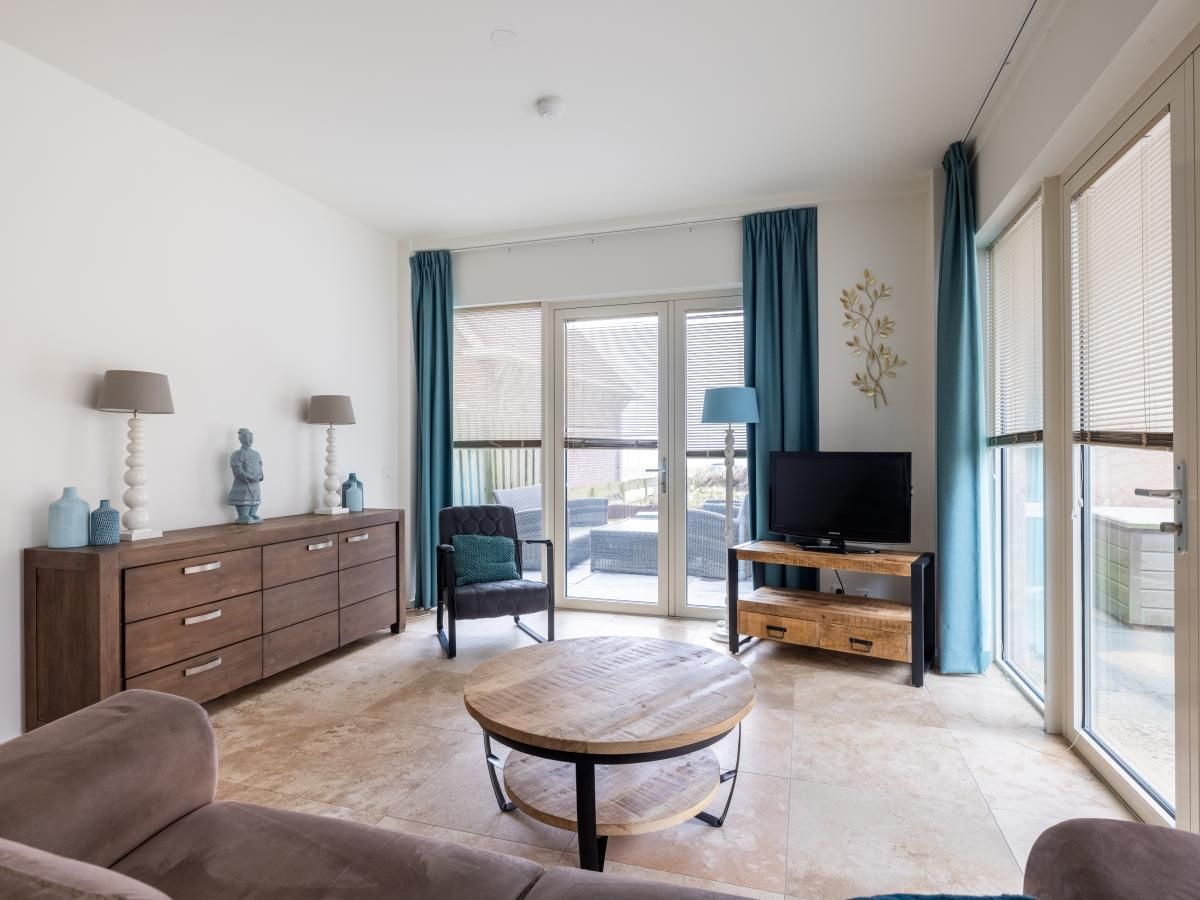 Cozy living room of vacation home De Platvis in Egmond aan Zee, North Sea coast, North Holland, with comfortable furnishings and a view of the terrace.