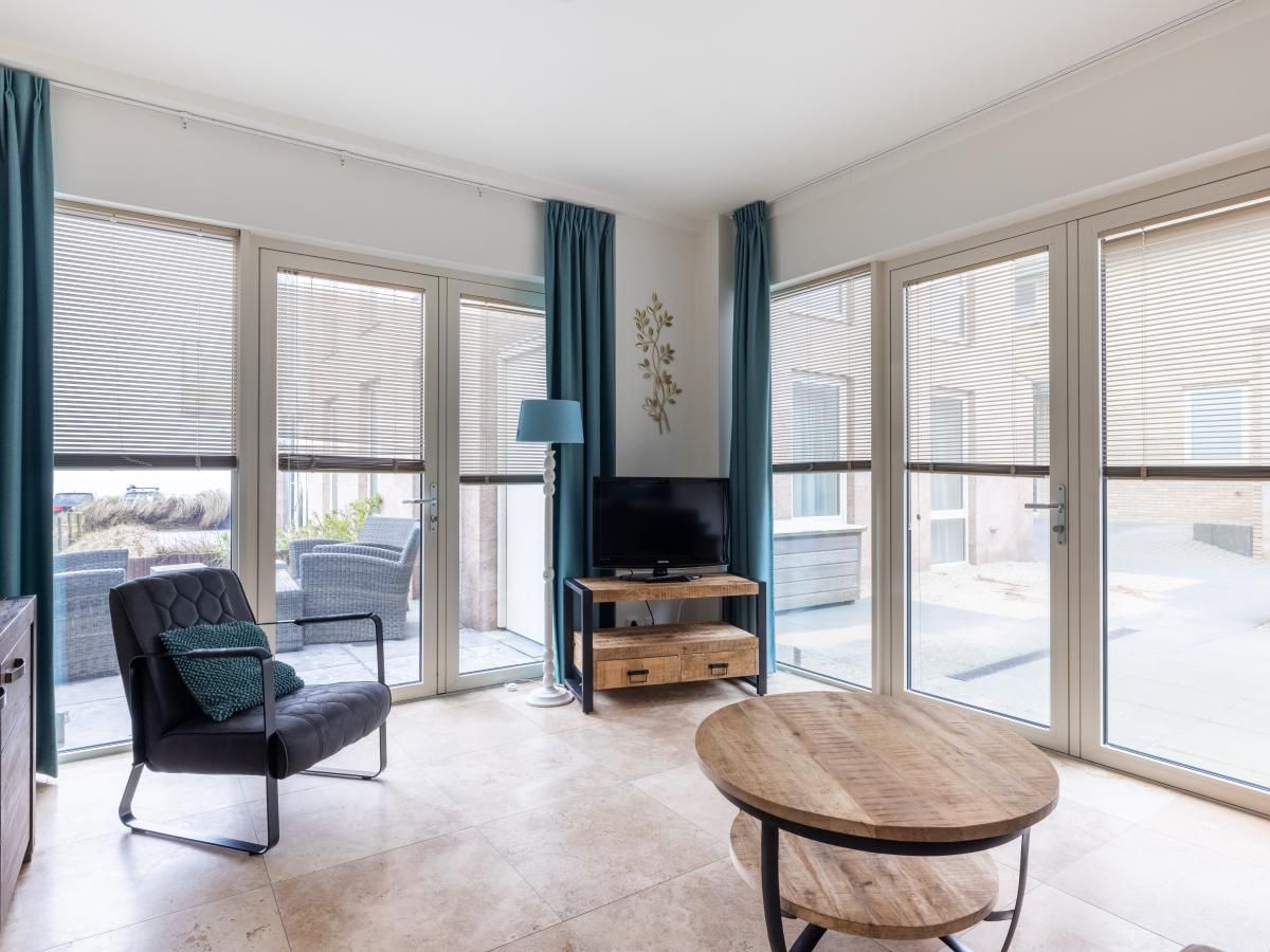 Bright living room in holiday home De Platvis, Egmond aan Zee, with large windows and modern furnishings on the North Sea coast in North Holland.