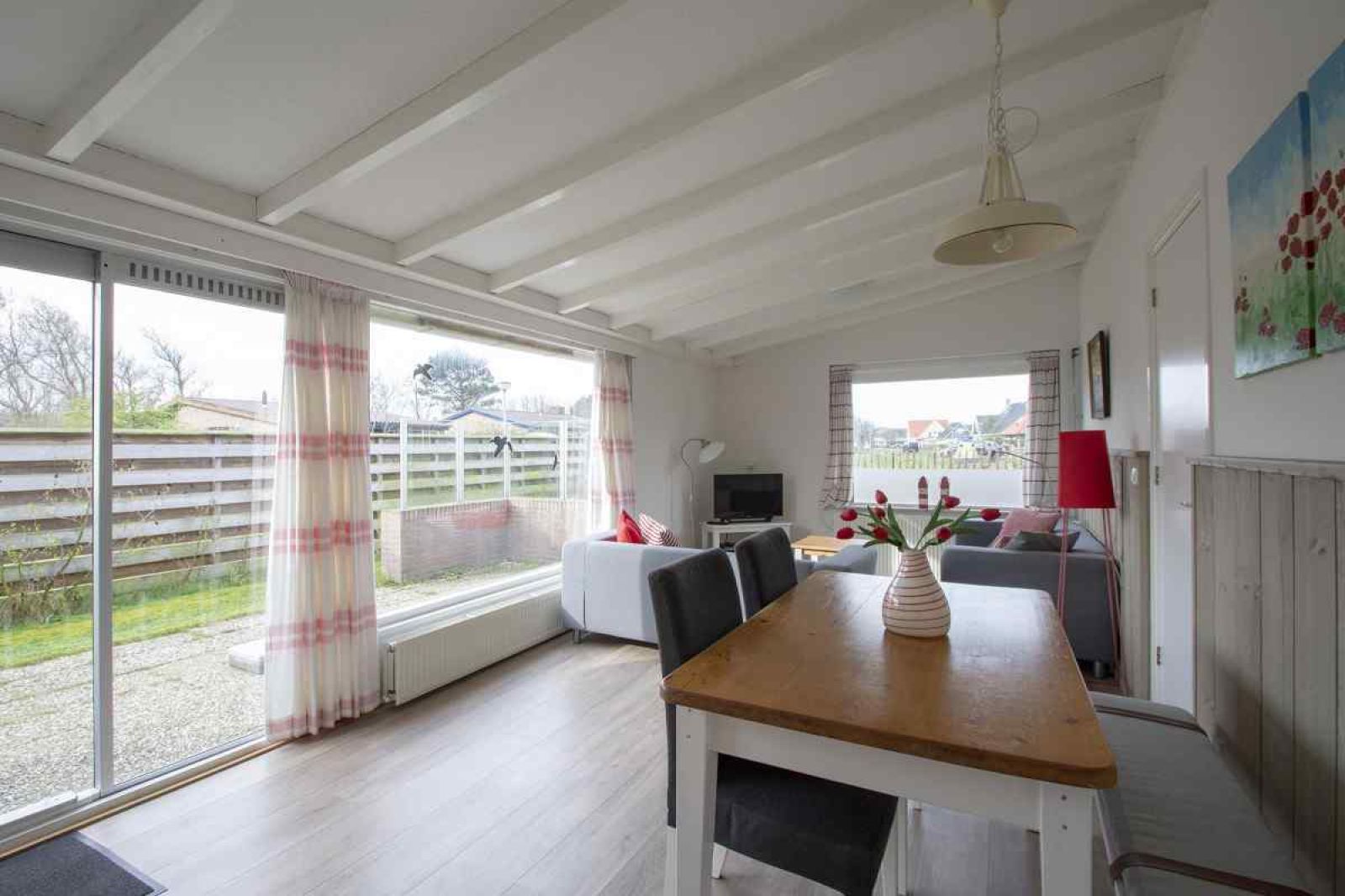 Gezellige woonkamer van vakantiehuis NH252 in Callantsoog, Noordzeekust. Licht interieur met uitzicht op de tuin, perfect voor ontspanning.