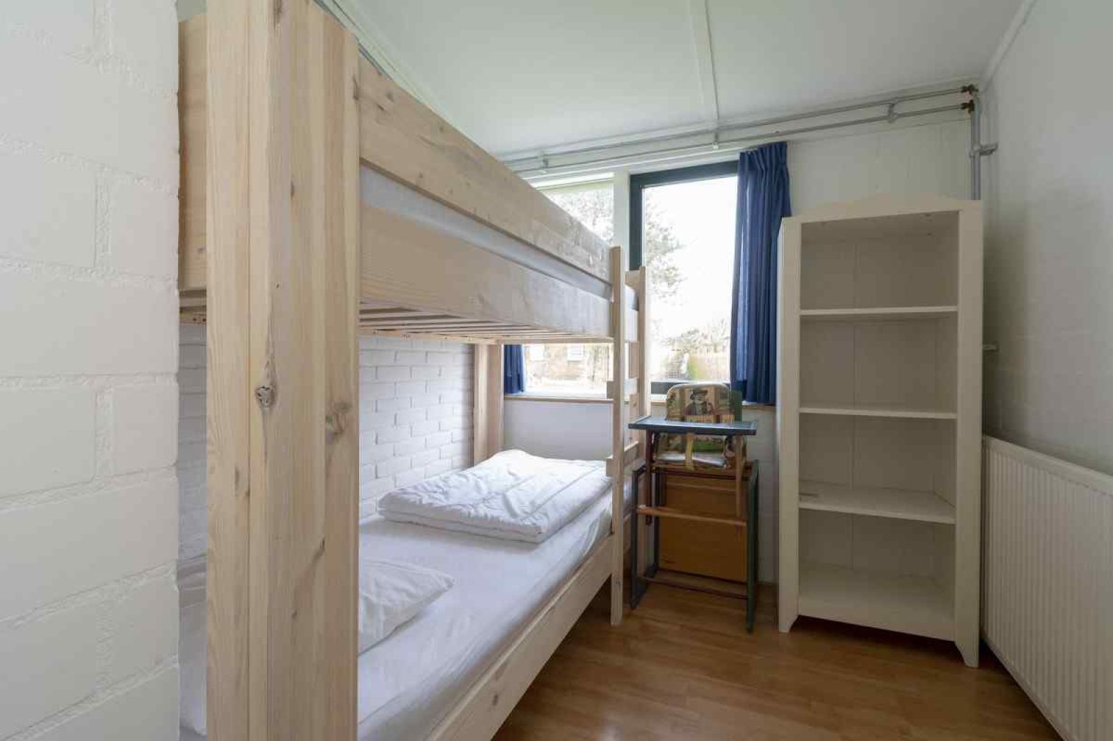 Slaapkamer in vakantiehuis NH252 in Callantsoog, Noordzeekust, Noord-Holland, met uitzicht op de groene omgeving.